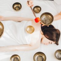 Young beautiful girl doing massage therapy singing bowls in the Spa. The concept of relaxation and alternative medicine. Toning.